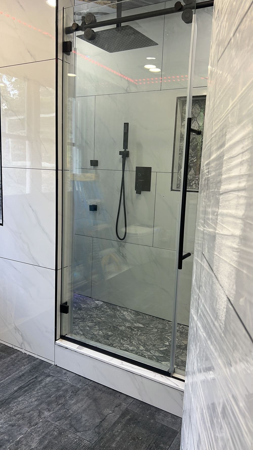 Modern glass shower with black fixtures and marble tile design in a stylish bathroom.