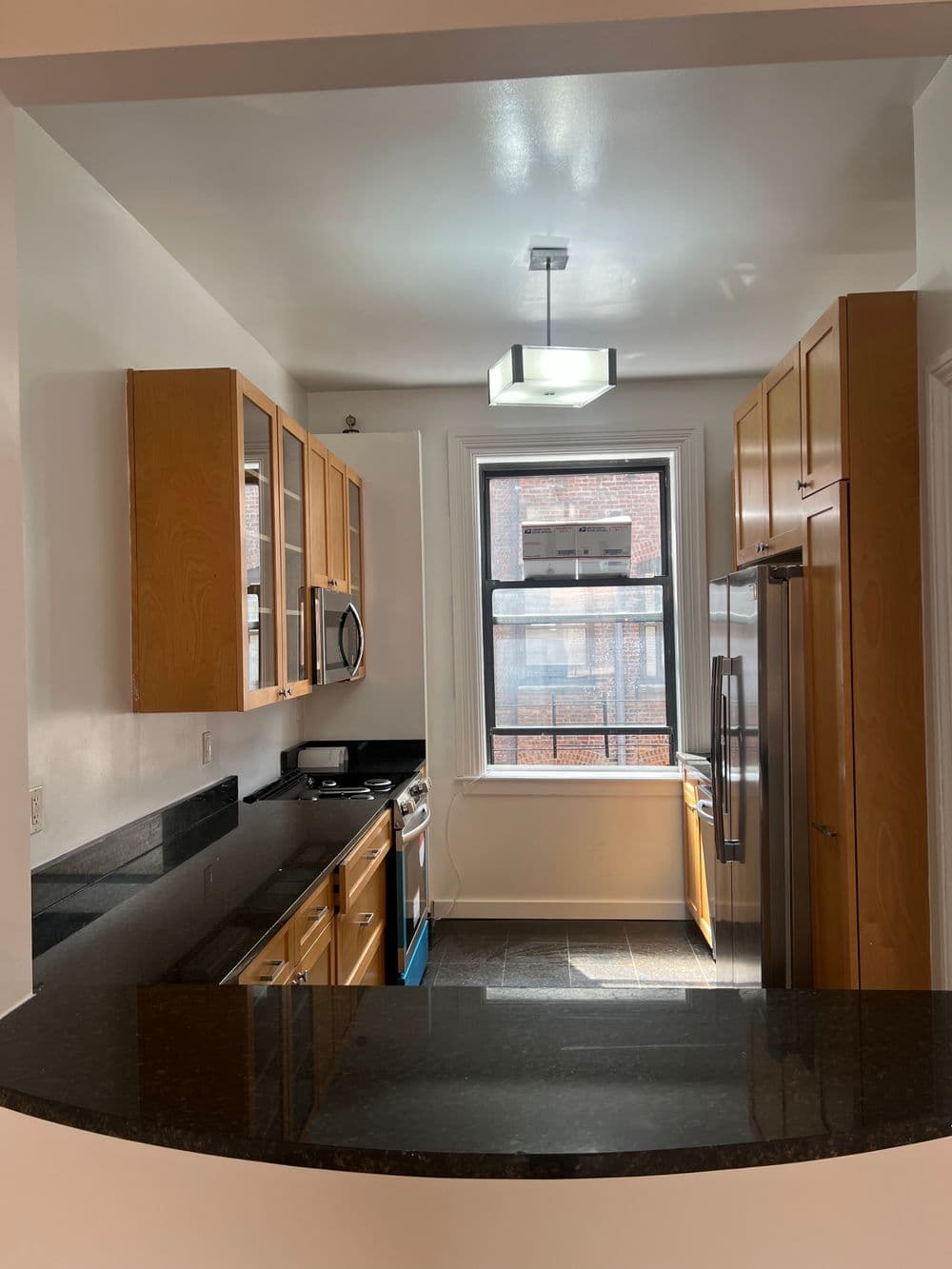 Modern kitchen with wooden cabinets, stainless steel appliances, and natural light from a window.