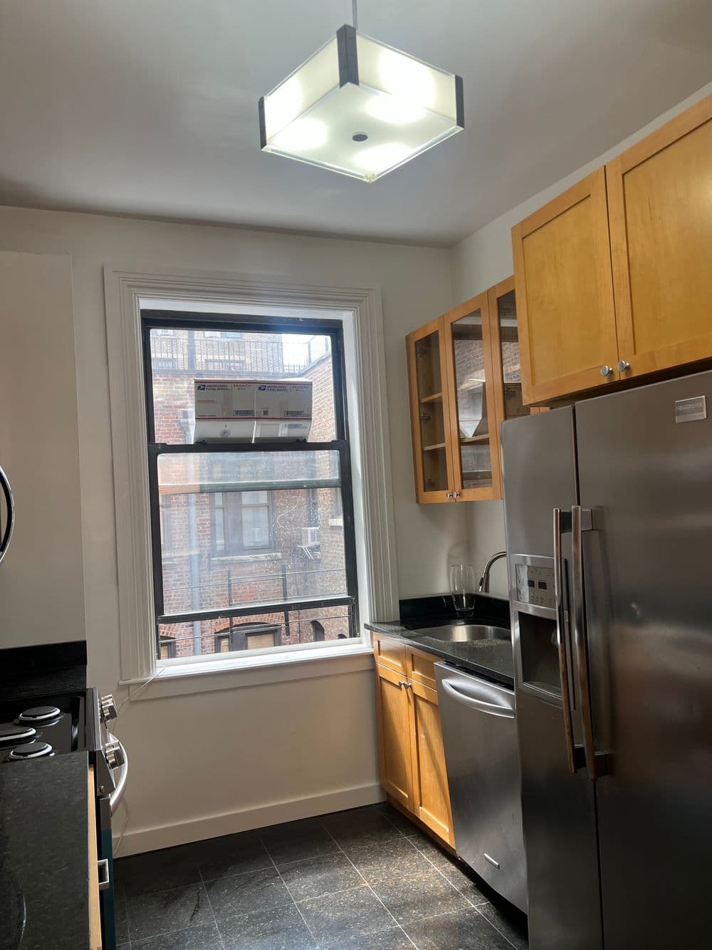 Modern kitchen with stainless steel appliances, wooden cabinets, and natural light from window.
