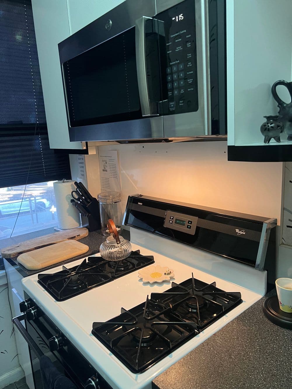 Modern kitchen featuring a stainless steel microwave above a gas stove with utensils and cooking accessories.