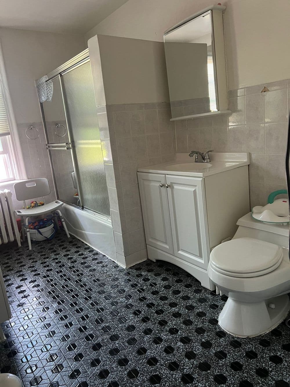 Modern bathroom featuring a shower, bathtub, white vanity, and black tiled flooring.