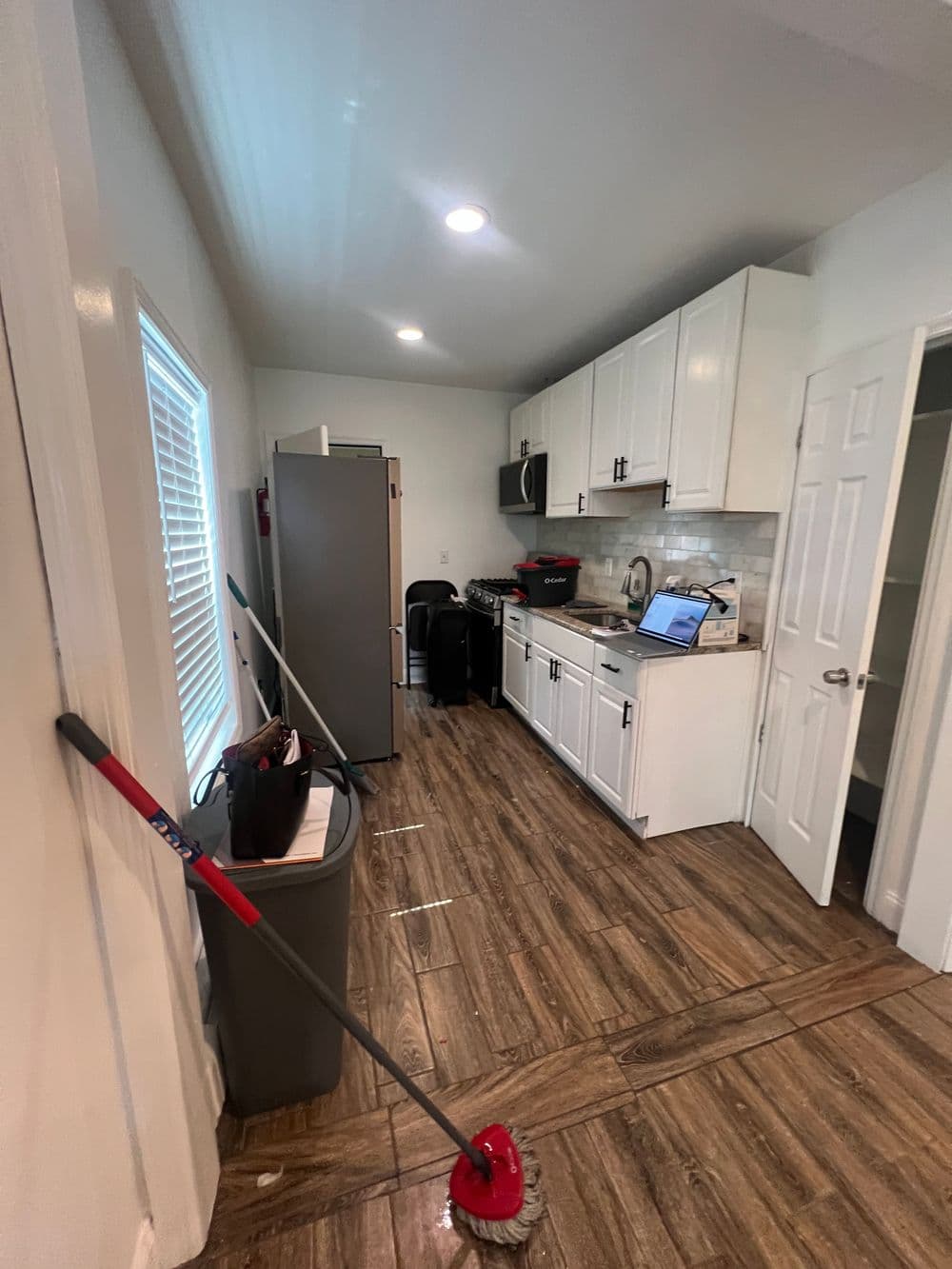 Modern kitchen with white cabinetry, stainless steel appliances, and clean tile flooring.