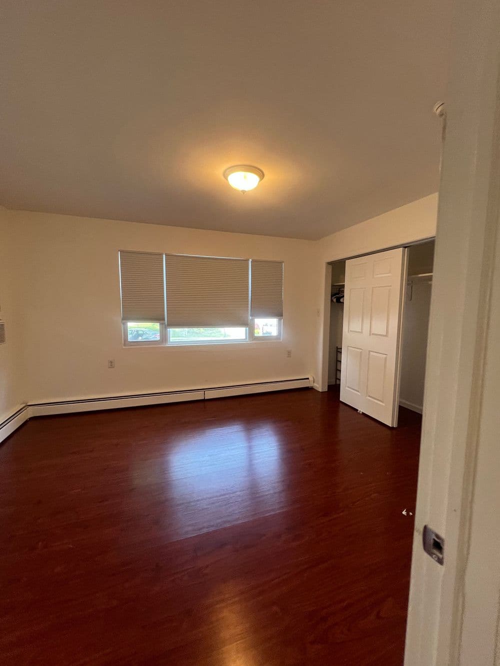 Spacious bedroom with hardwood floors, large windows, and closet space.
