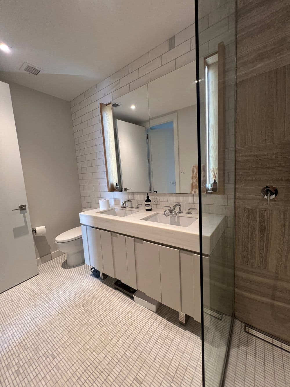 Modern bathroom with double sink, large mirror, and stylish tile flooring. Natural light included.