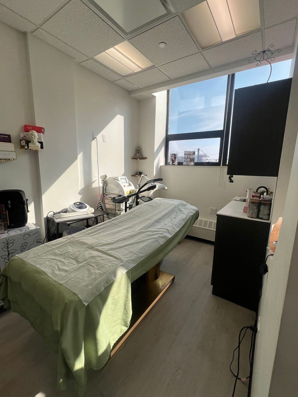 Bright and clean aesthetic treatment room with a massage table and modern equipment.