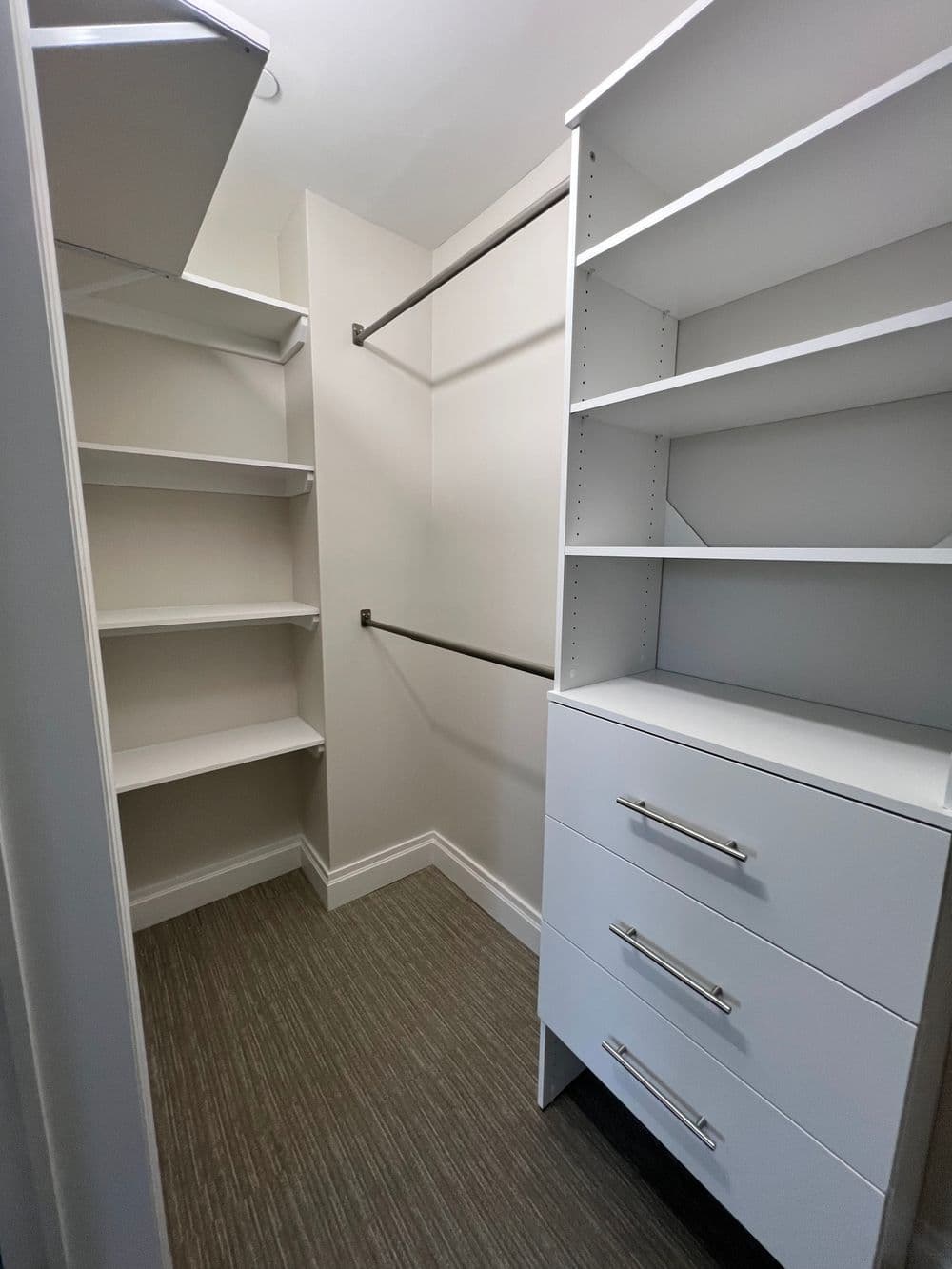 Spacious walk-in closet with shelving and drawers for organized storage.